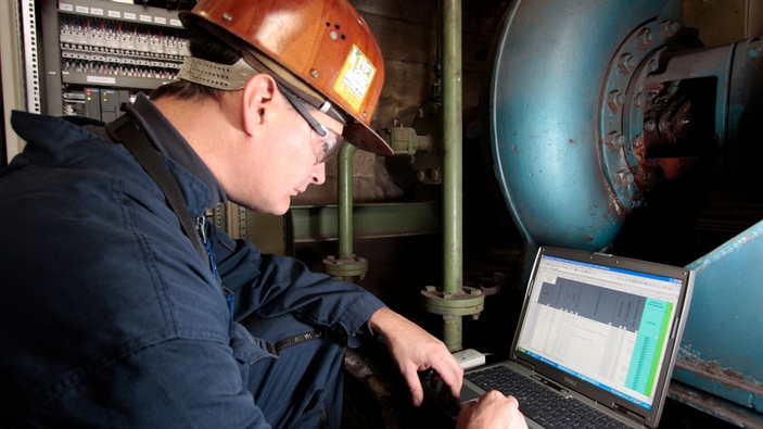 Man wearing hard hat looking at a laptop