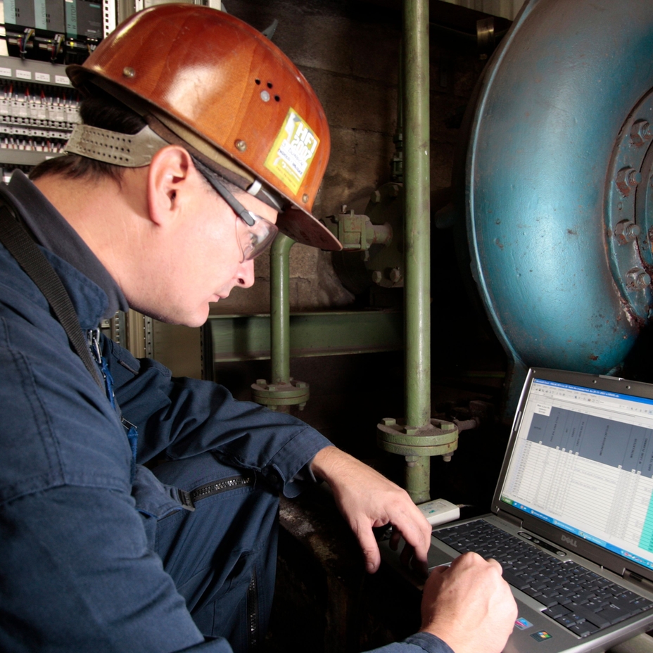 Man wearing hard hat looking at a laptop