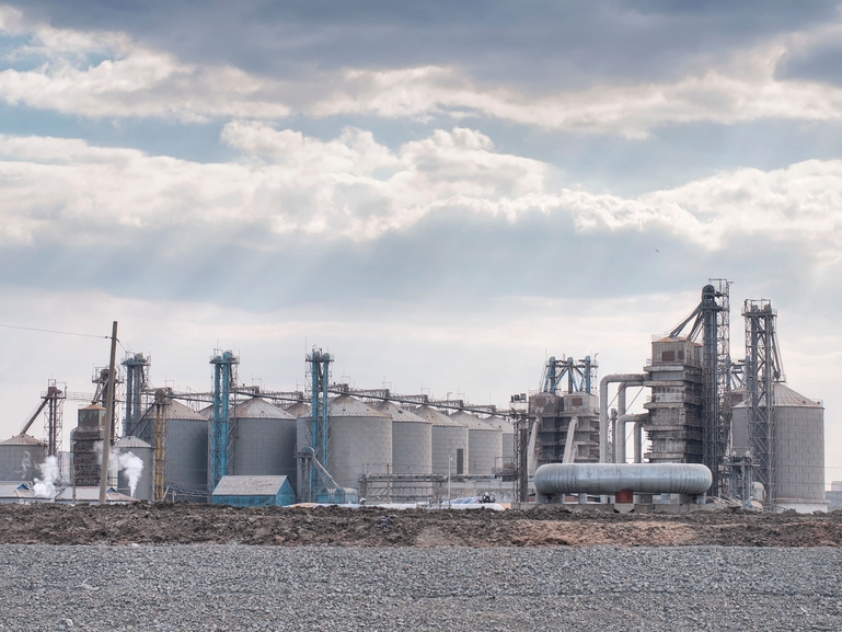 Industrial biofuel or biopolymer plant with storage tanks, processing towers and pipelines