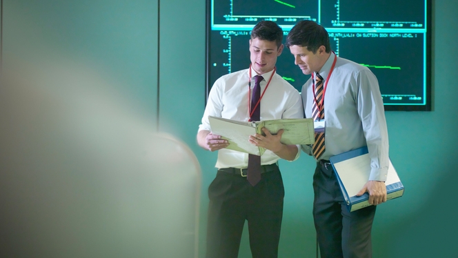 Two men stood in front of a screen looking at a folder