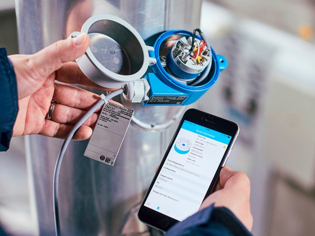 An Endress+Hauser device open with a man holding a smart device to conduct maintenance via Bluetooth