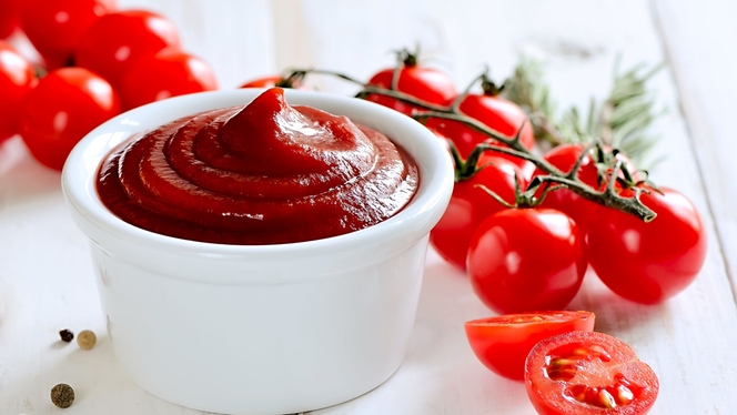 Picture of Ketchup in a white bowl with tomatoes in the background