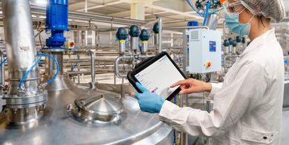 Woman standing in production facility and checking the Netilion Asset Health status