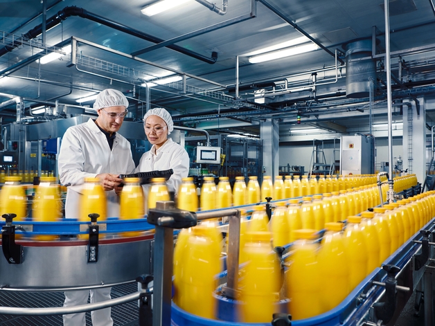 饮料厂中两名工程师在监测橙汁灌装过程。