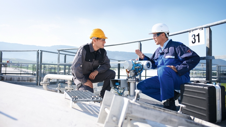 Customer and Endress+Hauser engineer discussing on the top of a tank.